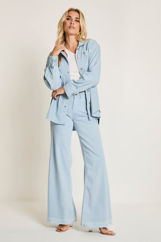 Woman wearing a light blue suit with a white shirt on a beige background